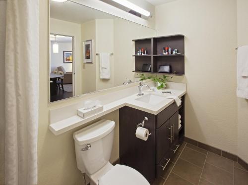 a bathroom with a toilet and a sink and a mirror at Candlewood Suites North Little Rock, an IHG Hotel in North Little Rock