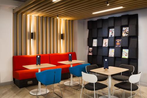 a restaurant with two tables and a red couch at Holiday Inn Express London-Ealing by IHG in London