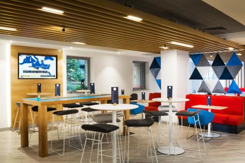 a restaurant with tables and stools in a room at Holiday Inn Express London-Ealing by IHG in London