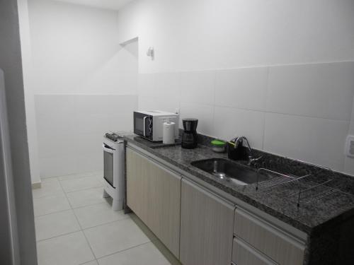 eine Küche mit einer Spüle und einer Mikrowelle in der Unterkunft Aconchego e Requinte no Centro in Petrópolis