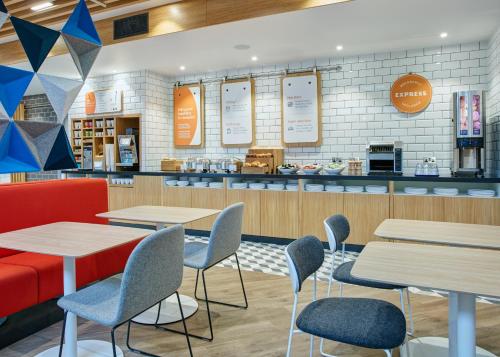 a restaurant with tables and chairs and a counter at Holiday Inn Express London-Ealing by IHG in London