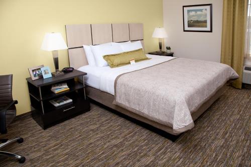 ein Hotelzimmer mit einem großen Bett und einem Nachttisch in der Unterkunft Candlewood Suites North Little Rock, an IHG Hotel in North Little Rock