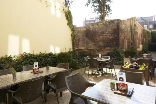 a patio with tables and chairs and a wall at Holiday Inn Express Hasselt by IHG in Hasselt