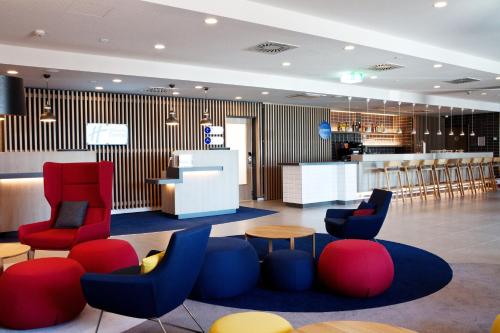 lobby z czerwonymi i niebieskimi krzesłami oraz barem w obiekcie Holiday Inn Express - Ringsheim, an IHG Hotel w mieście Ringsheim