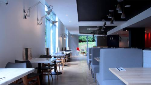 a dining room with tables and chairs and windows at Holiday Inn Express London Stansted Airport by IHG in Stansted Mountfitchet