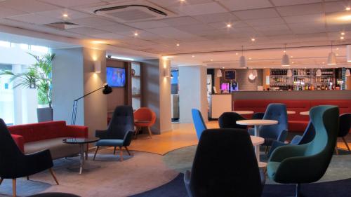 a lobby with chairs and tables and a bar at Holiday Inn Express London Stansted Airport by IHG in Stansted Mountfitchet