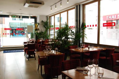 a restaurant with tables and chairs and windows at Hotel Indigo London Tower Hill by IHG in London