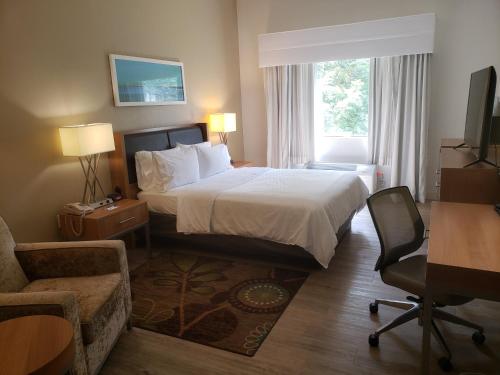 a hotel room with a bed and a chair at Holiday Inn Express Hotel Pittsburgh-North/Harmarville by IHG in Harmarville
