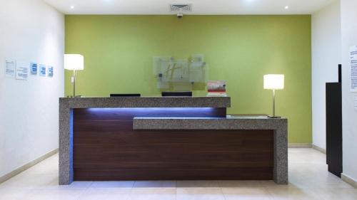 a reception desk in a room with a green wall at Holiday Inn Express Xalapa by IHG in Xalapa
