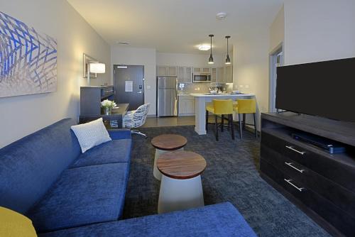 a living room with a blue couch and a kitchen at Staybridge Suites - Little Rock - Medical Center by IHG in Little Rock
