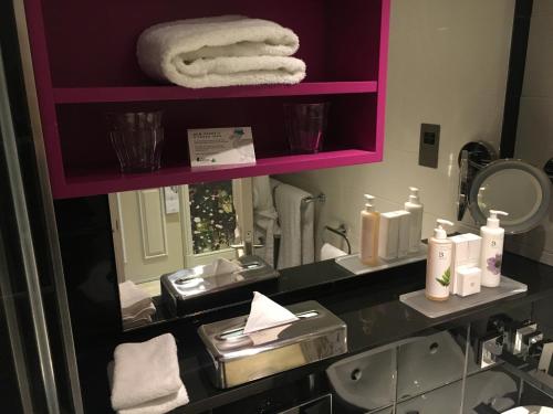 a bathroom with a sink and a mirror with towels at Hotel Indigo London - Kensington by IHG in London