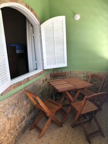 two wooden tables and chairs sitting under two windows at O Mar Hospedagem - SUÍTES PRIVADAS in Arraial do Cabo