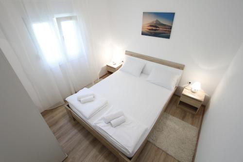 - une petite chambre blanche avec un lit blanc et une fenêtre dans l'établissement Holiday home Olive, à Privlaka