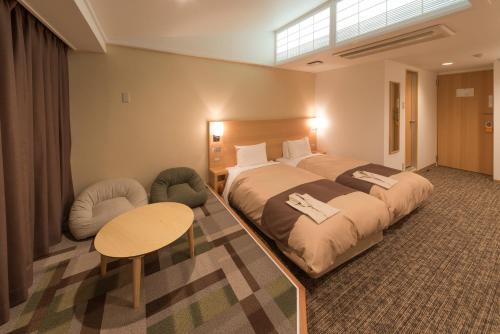 a bedroom with a large bed and a table and chairs at Hachinohe Park Hotel in Hachinohe