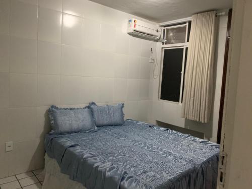 Schlafzimmer mit einem Bett mit blauer Bettwäsche und einem Fenster in der Unterkunft Apto mobiliado no Jardim Renascenca in São Luís