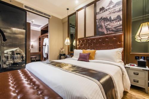 a bedroom with a large bed with a leather headboard at Metropole Bangkok in Bangkok