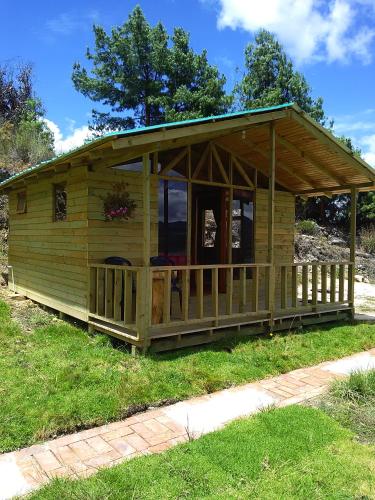 a large wooden cabin with a porch on the grass at Cabaña San Martin in Guatavita