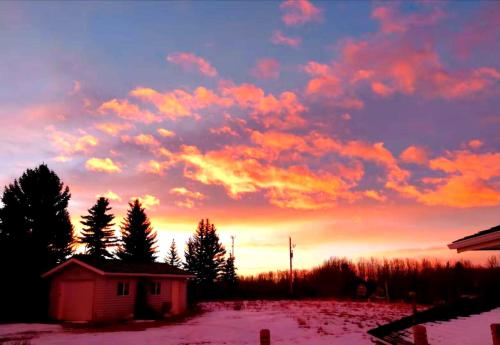 a sunset over a field with a house and trees at Green Village in Calgary