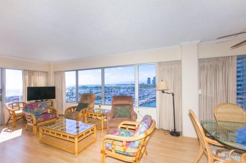 un soggiorno con divano, sedie e TV di Ilikai Tower 943 Condo - Walk to the Beach, Shops & Restaurants! a Honolulu