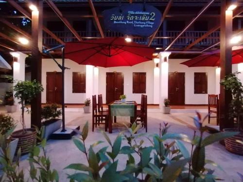 a patio with a table and a red umbrella at Villa Chitchareune 2 in Luang Prabang