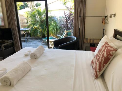 a bedroom with a white bed with towels on it at Tairua Shores Motel in Tairua