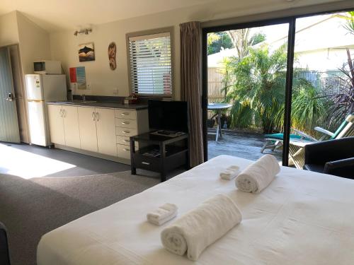 Tairua Shores Motel في تايروا: غرفة نوم بسرير ابيض عليها مناشف