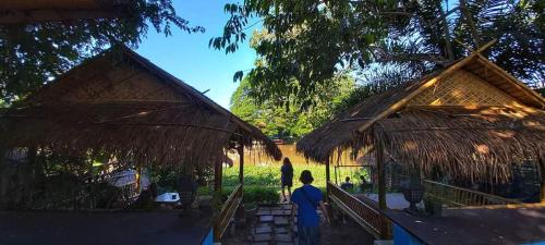 two people walking in front of two straw huts at Mapping Hostel in Chiang Mai