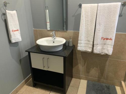 a bathroom with a sink and a mirror and towels at Durban Waterfront Apartments in Durban