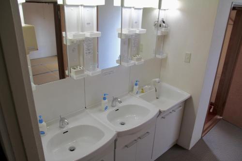 a white bathroom with two sinks and a mirror at City Pension Tommy Rich Inn Kyoto in Kyoto