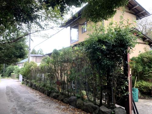 a fence in front of a house with trees at 熱海 櫂雲 (Atami-Kaiun) in Ajiro