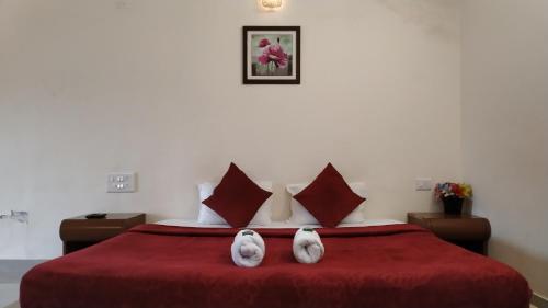two white rabbits sitting on a red bed at Bluebell Residency in Mahabaleshwar