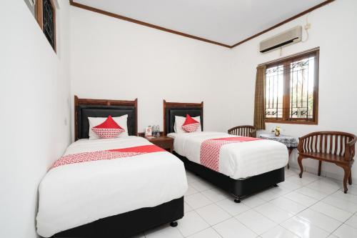 a bedroom with two beds and a table and chairs at Hotel O Omah Duwet in Yogyakarta