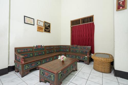 a room with two benches and a table with flowers at Hotel O Omah Duwet in Yogyakarta