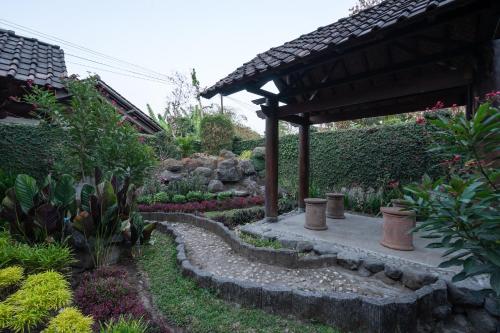 a garden with a pergola and a stone path at Hotel O Omah Duwet in Yogyakarta