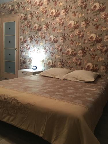 a bedroom with a bed with a floral wall at Apartments at Laureatov 43 in Noril'sk
