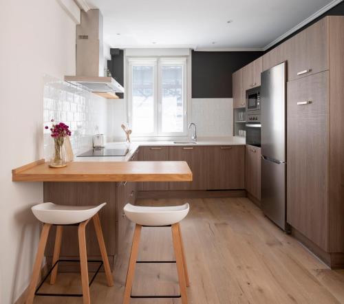 a kitchen with wooden cabinets and a kitchen island with stools at PREMIUM LOCATION! Gran Vía & FREE Parking in Bilbao
