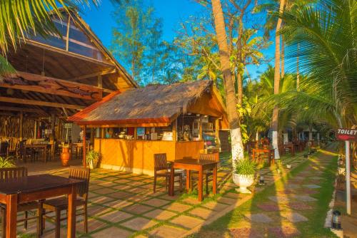 un restaurante con mesas, sillas y palmeras en COCONUT BEACH LODGE en Trincomalee