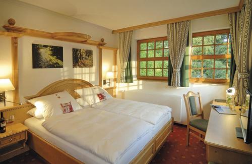 a bedroom with a bed and a desk with a computer at Alpenhof in Gauting