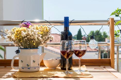 a table with two glasses of wine and a vase of flowers at Narancin Apartments in Trogir