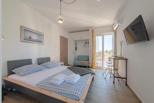 a bedroom with a bed with blue pillows and a television at Narancin Apartments in Trogir
