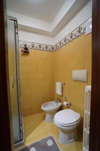 a yellow bathroom with a toilet and a shower at Aretè Apartments in Lecce