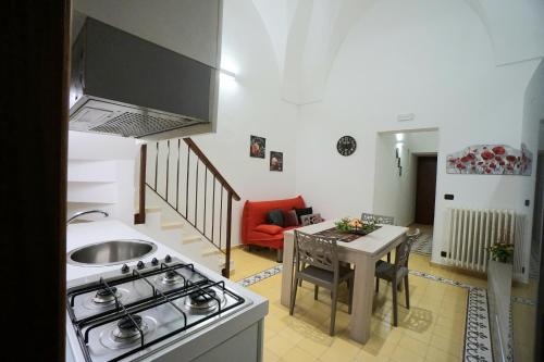Aretè Apartments في ليتشي: مطبخ وغرفة معيشة مع موقد وطاولة