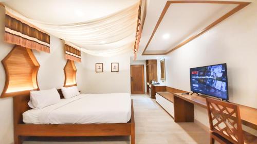 a bedroom with a bed and a flat screen tv at Big Tree Old Town Hotel in Chiang Mai