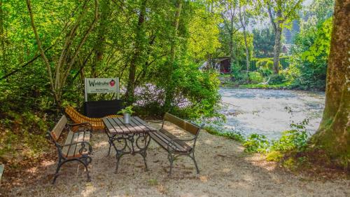 a picnic table and two chairs next to a river at Waldruhe - Bett, Frühstück & ein Lächeln in Bad Aussee