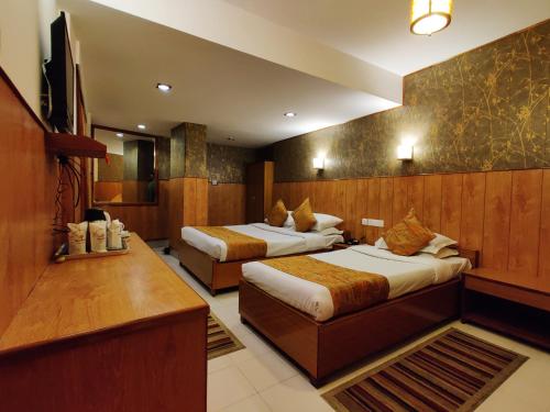 a hotel room with two beds and a television at Hotel Tarayana in Gangtok