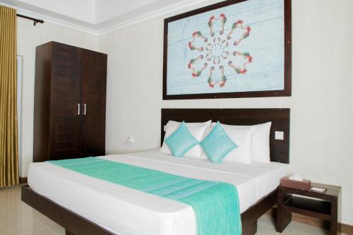 a bedroom with a large white bed with blue pillows at Seahorse Hotel & Spa in Negombo