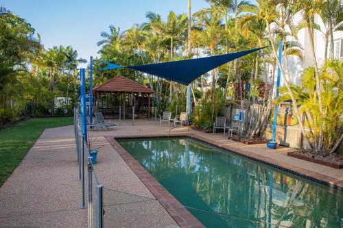 a swimming pool with a blue umbrella over it at Tripcony Quays in Caloundra