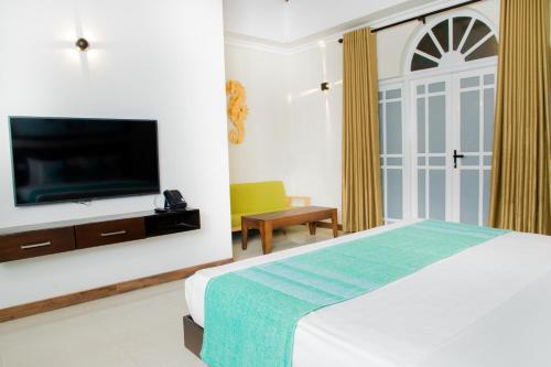 a bedroom with a bed and a flat screen tv at Seahorse Hotel & Spa in Negombo