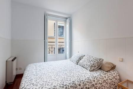 - une chambre blanche avec un lit et une fenêtre dans l'établissement Apartamento La Latina I, à Madrid