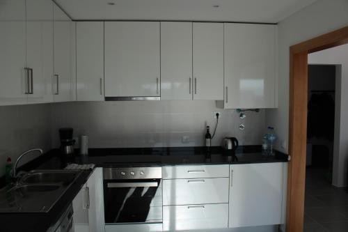a kitchen with white cabinets and a stove and a sink at Bela Baia Holiday in Salir de Porto